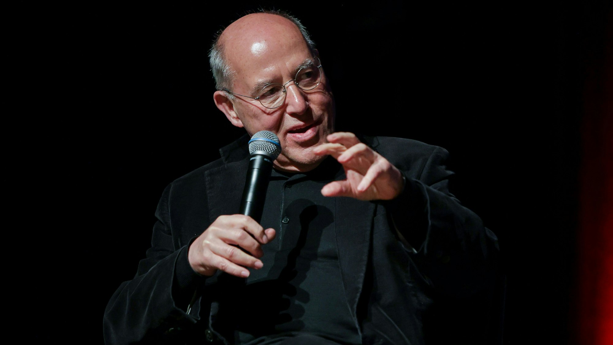 Gysi vor dunklem Hintergrund mit Mikro, er redet und gestikuliert.