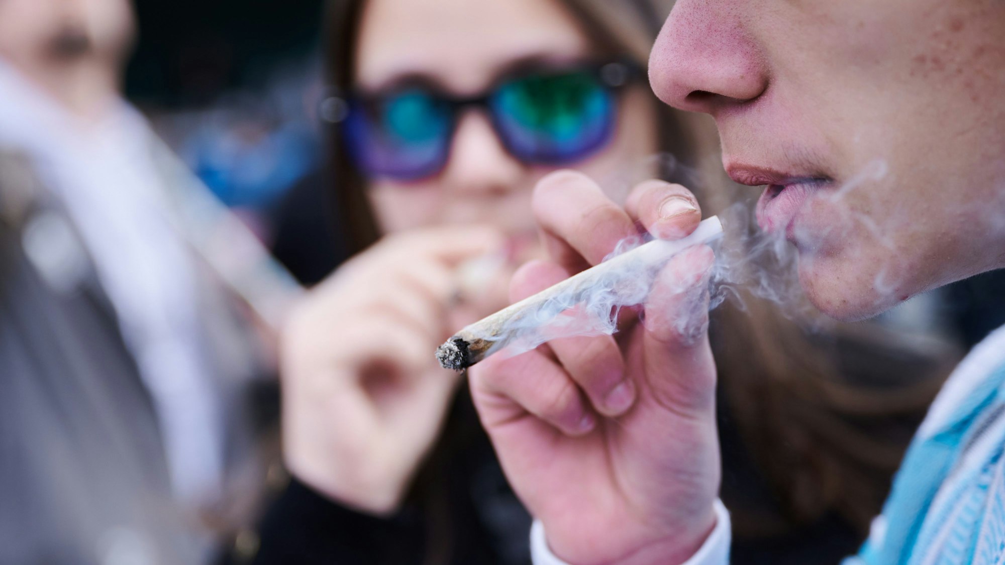 Ein junger Mann raucht einen Joint.