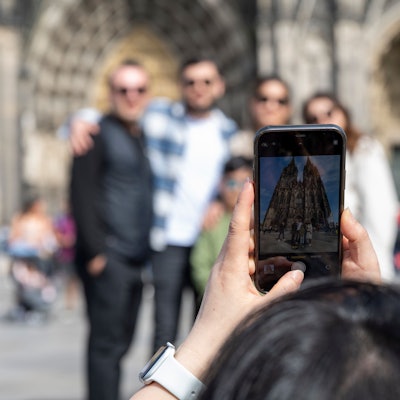 Eine Frau fotografiert Touristen vor dem Dom.