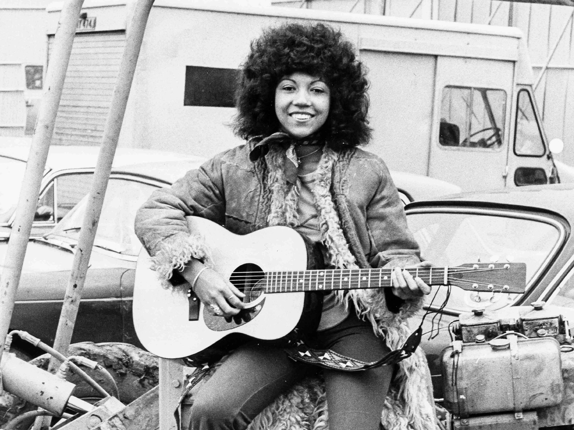 Linda Lewis sitzt mit ihrer Gitarre auf einem Traktor.