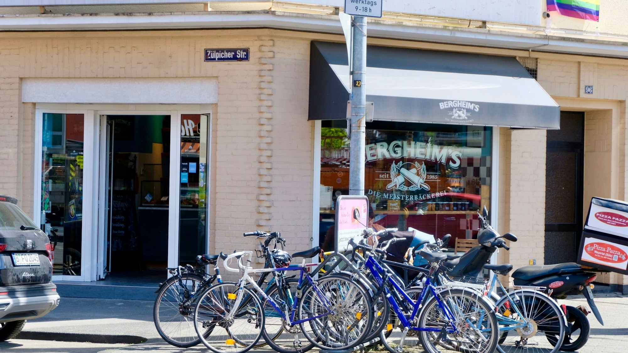 Viele Fahrräder stehen vor der Glasfront eines Eck-Ladenlokals.