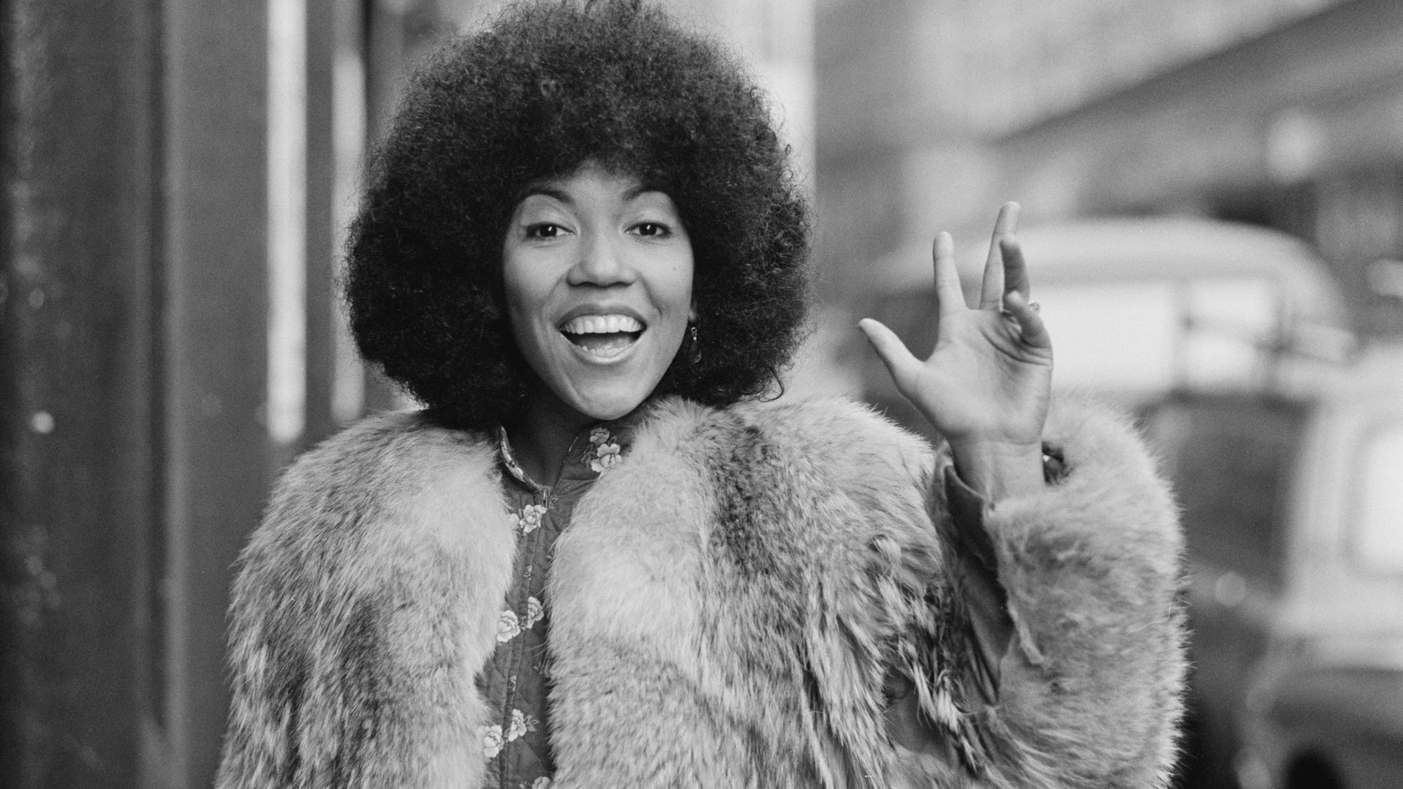 Die englische Sängerin, Songschreiberin und Gitarristin Linda Lewis winkt.