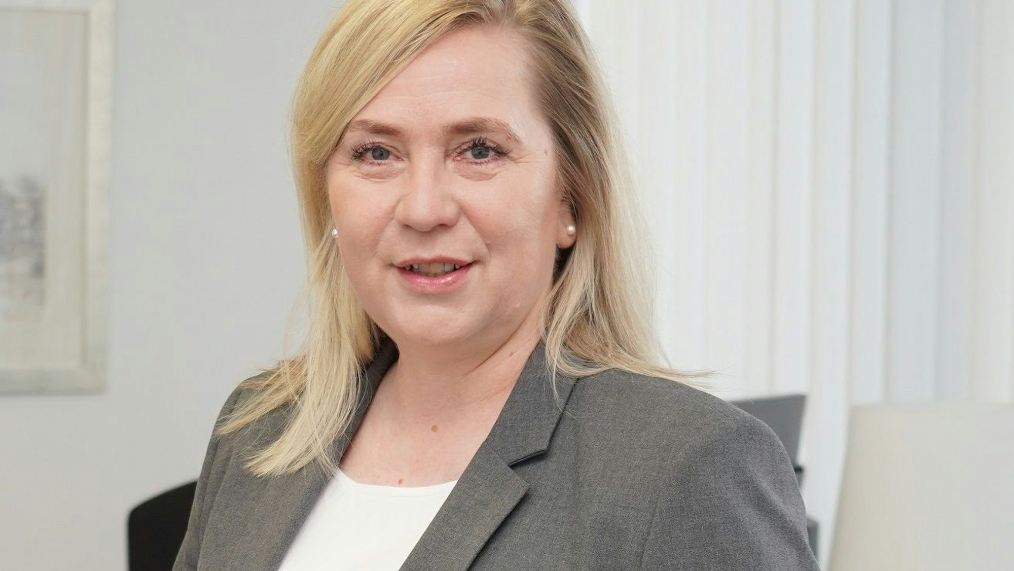 Auf dem Foto ist ein Portrait von Frechens Bürgermeisterin Susanne Stupp zu sehen, sie trägt ein weißes T-Shirt und ein graues Sakko.