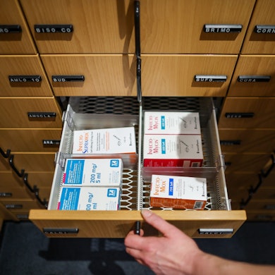 Eine Apothekerin öffnet eine Schublade mit Medikamenten.