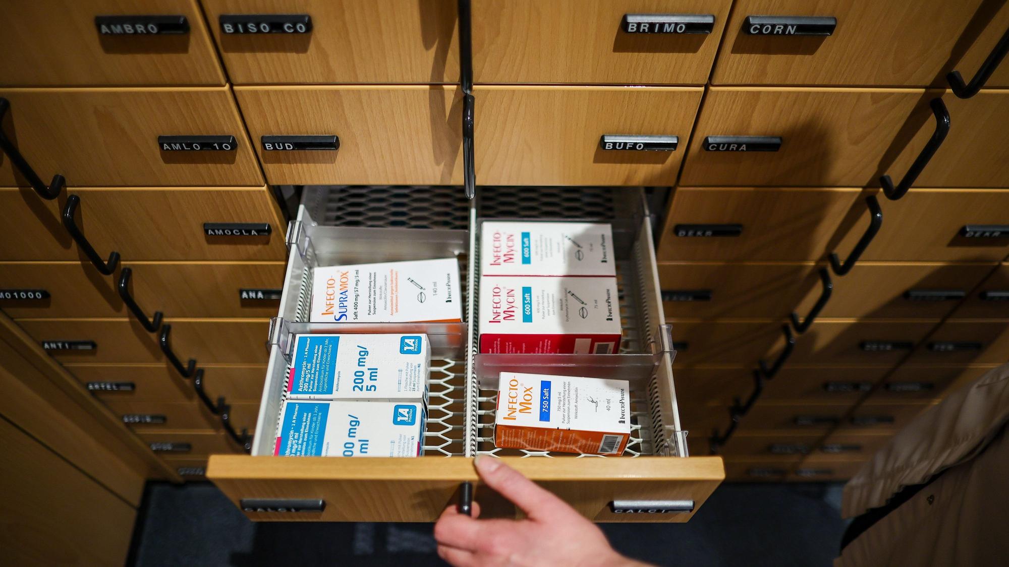 Eine Apothekerin öffnet ein Schubfach mit Antibiotikasäften für Kinder.
