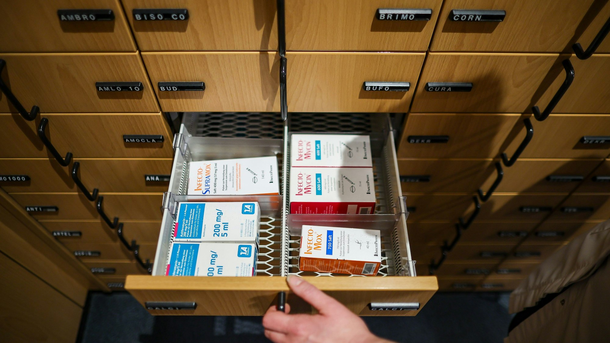 Eine Apothekerin öffnet ein Schubfach mit Antibiotikasäften für Kinder.