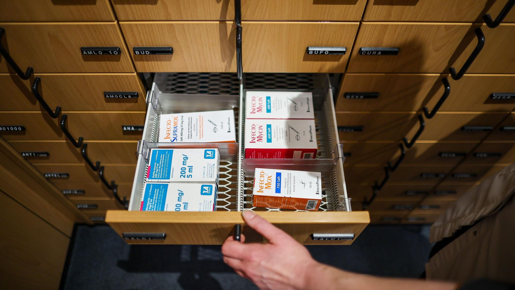 Eine Apothekerin öffnet ein Schubfach mit Antibiotikasäften für Kinder.