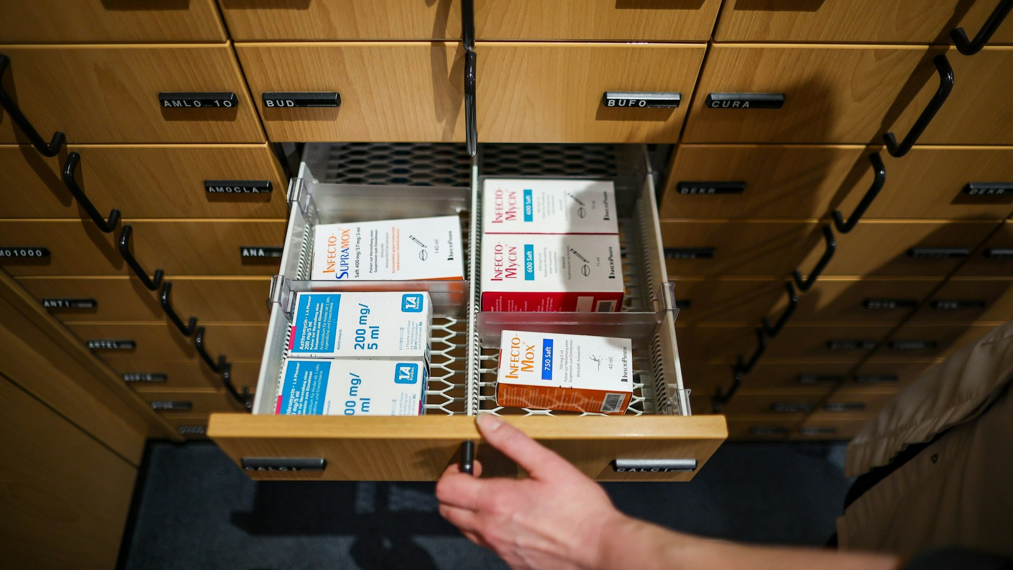 Eine Apothekerin öffnet ein Schubfach mit Antibiotikasäften für Kinder.