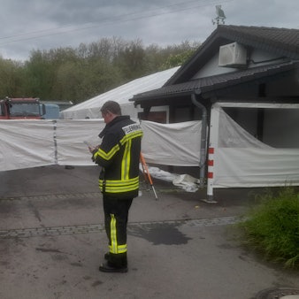 Ein Feuerwehrmann steht vor einer Sichtschutzplane.