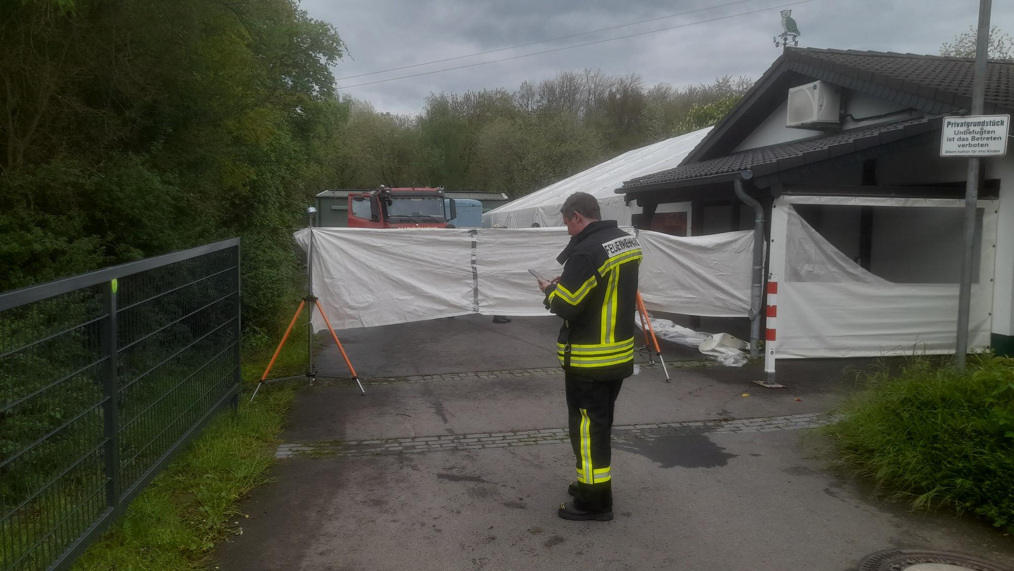 Ein Feuerwehrmann steht vor einer Sichtschutzplane.