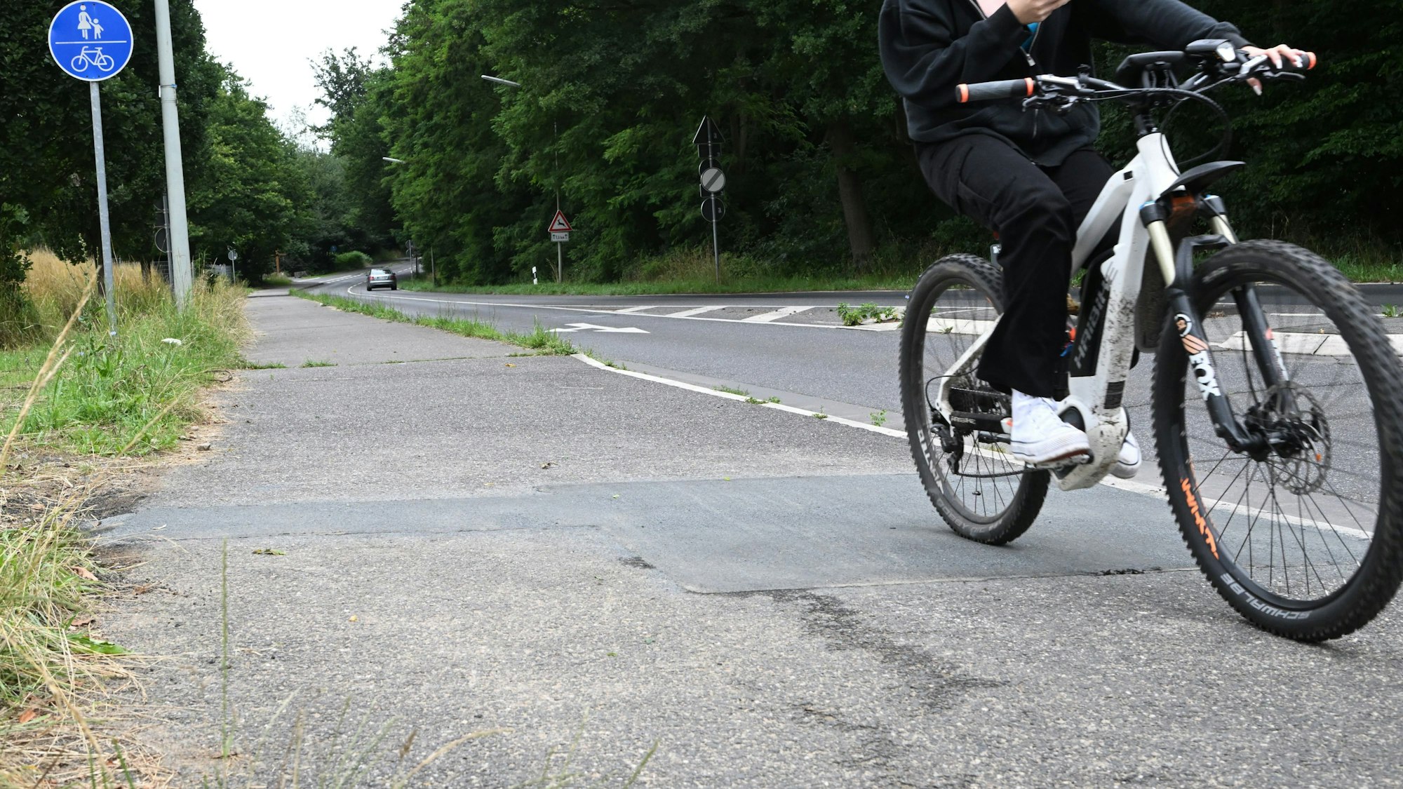 Der Radweg am Schulzentrum Rösrath. Rechts im Bild ist ein Fahrradfahrer zu sehen.