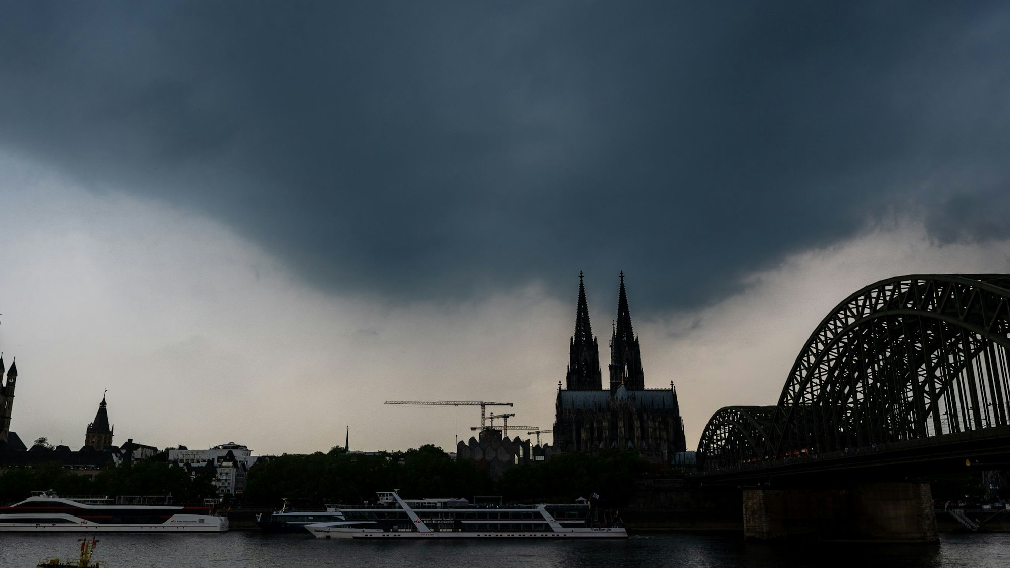 Dunkle Gewitterwolken ziehen über dem Kölner Dom auf. Der Deutsche Wetterdienst warnt vor unwetterartigen Gewittern mit Starkregen und Hagel im Rheinland. (Symbolbild)