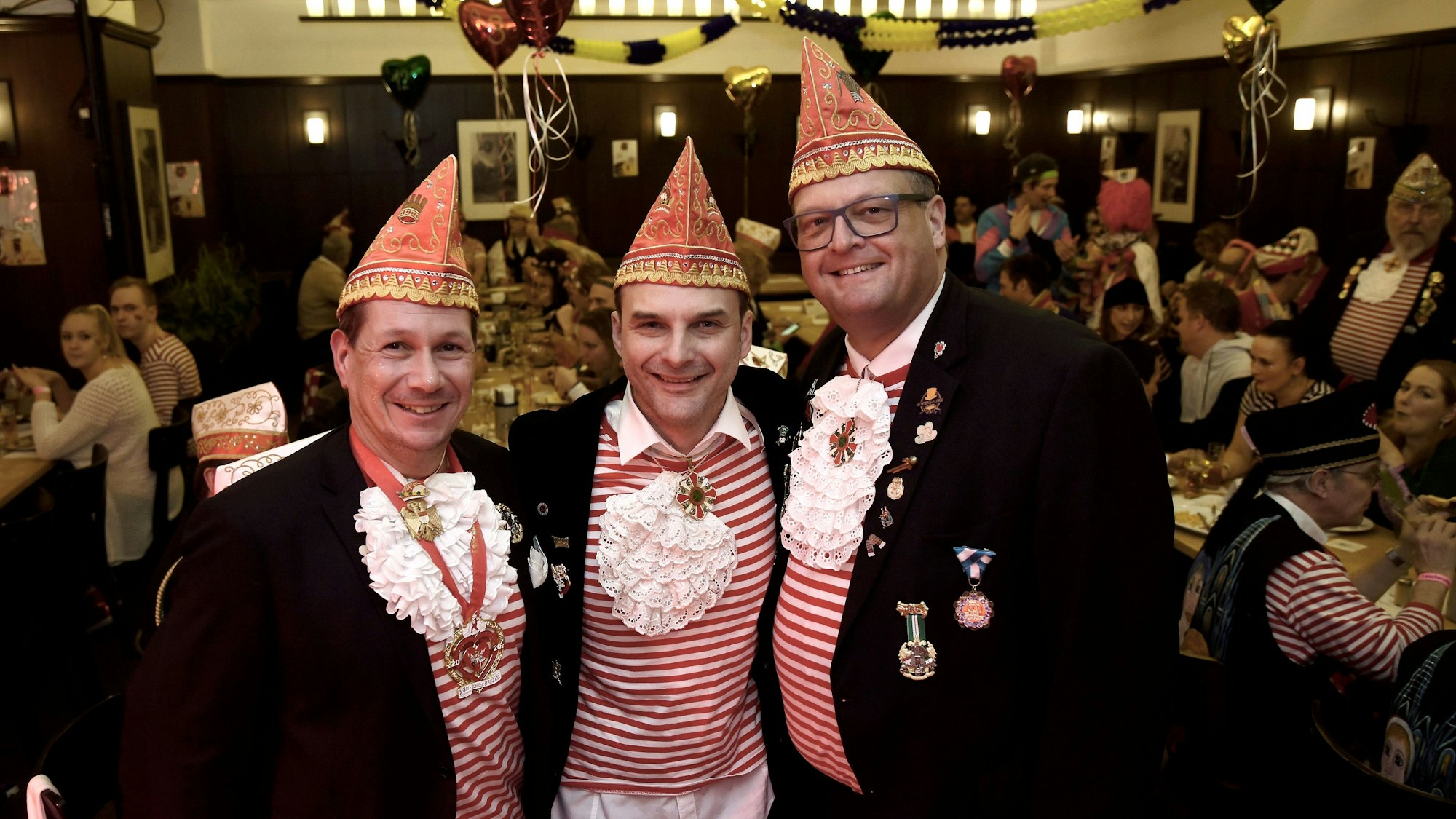 Drei Männer im Karnevalsoutfit in einer Kneipe