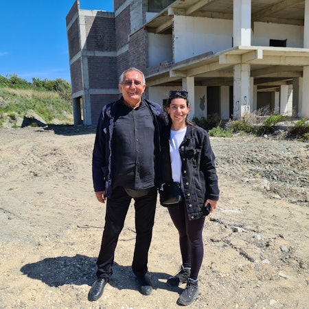 Lamia Faqirzada und Ali Koban stehen auf einem Grundstück im Erdbebengebiet in Hatay, auf dem die Kölner eine spendenfinanzierte Kita bauen wollen.