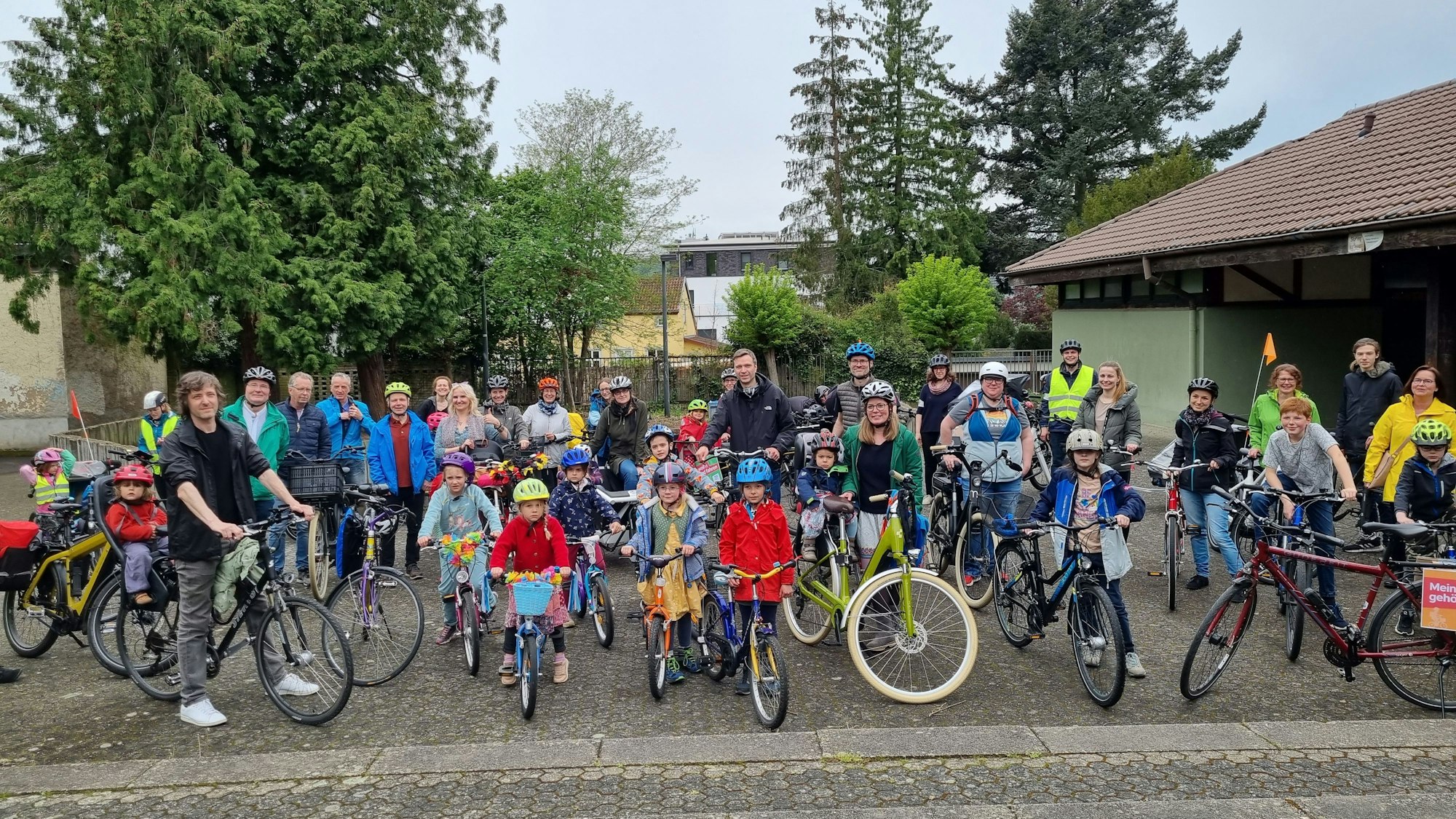 Eine Gruppe von Eltern und Kindern stellt sich mit ihren Rädern vor dem Start der Demonstration zum Gruppenbild. Die meisten tragen Fahrradhelme.