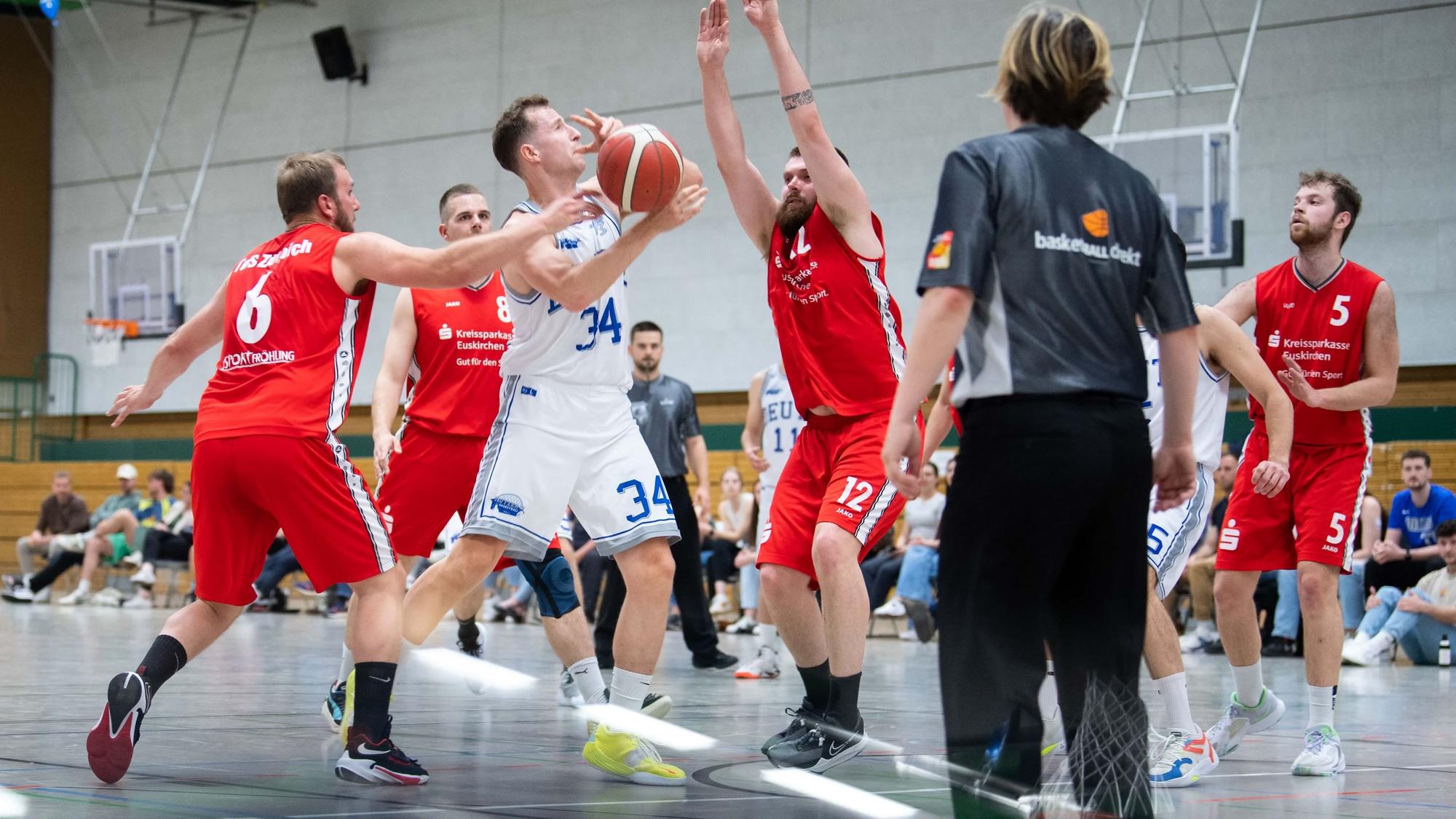 Ein Deutzer Spieler (in weißem Trikot) wird von den Zülpichern beim Korbleger gestört.