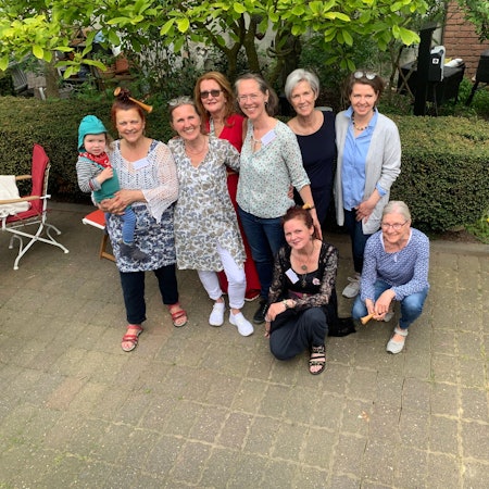 Das Gründungsteam des Hebammenhauses steht zusammen vor einer Hecke.