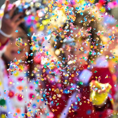 Karnevalisten werfen Konfetti.