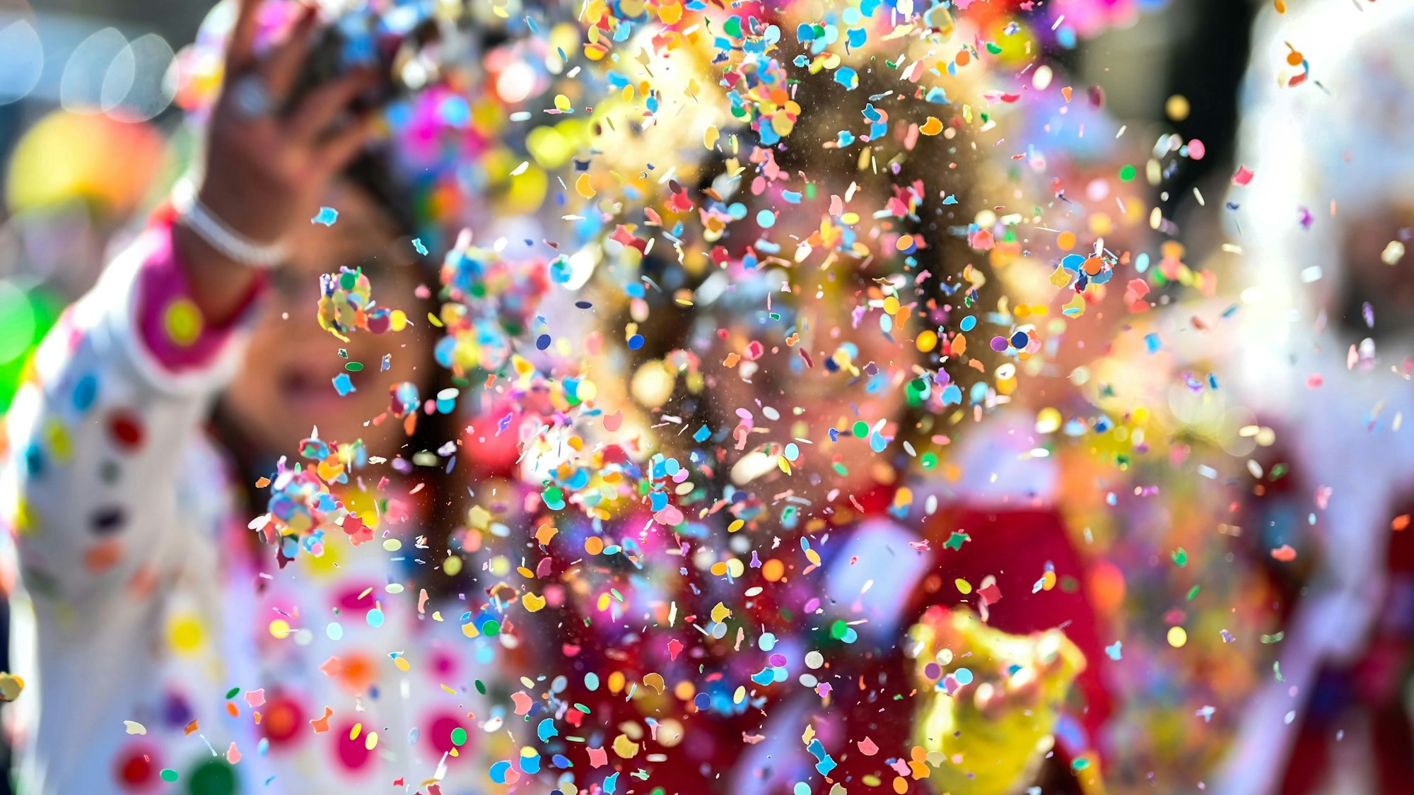Karnevalisten werfen Konfetti.