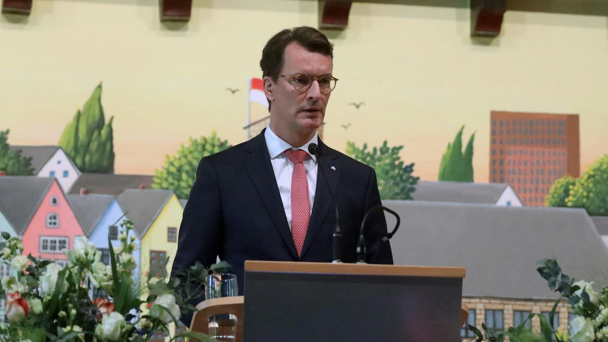 Wüst am Rednerpult, rechts die NRW-Flagge