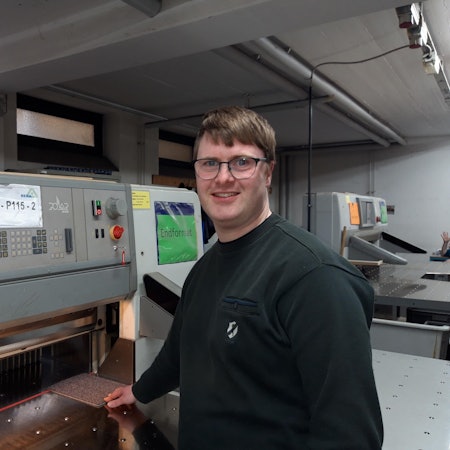 Ansgar Peters steht vor einer Polarschneidemaschine.