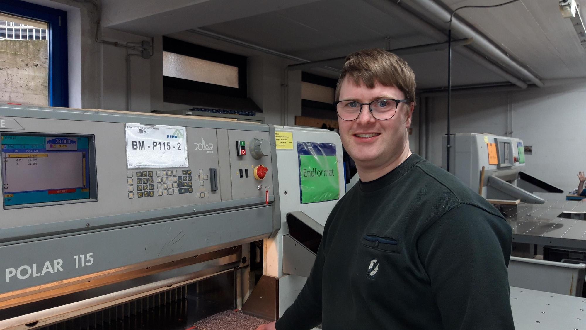 Ansgar Peters steht vor einer Polarschneidemaschine.