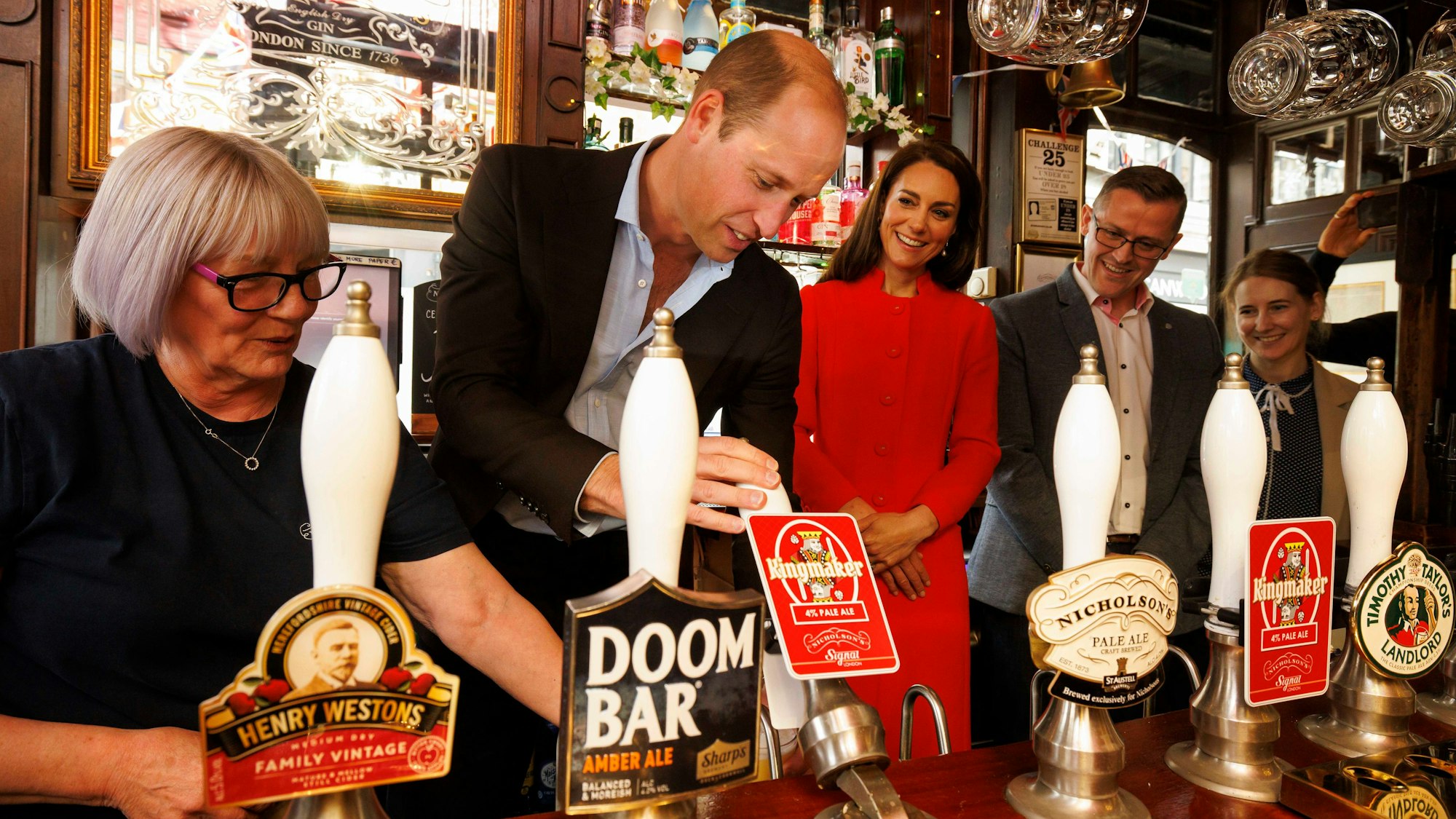 Prinz William, Prinz von Wales, zapft vor der Krönung am 4. Mai 2023 in London, England, im Dog and Duck Pub in Soho das erste Glas Kingmaker, ein neues Getränk zur Feier der Krönung, während Catherine, Prinzessin von Wales, zusieht.