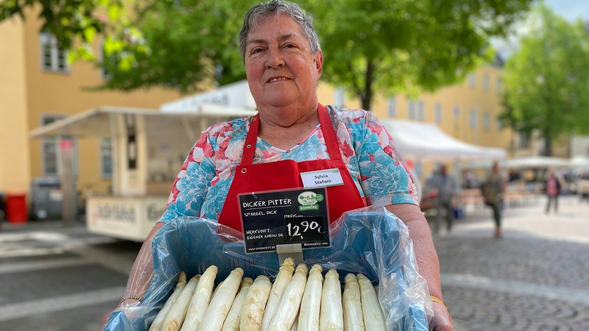 Eine Verkäuferin hält eine Kiste Spargel. Um ihn dreht es sich beim Wein- und Spargelfest in Brühl.