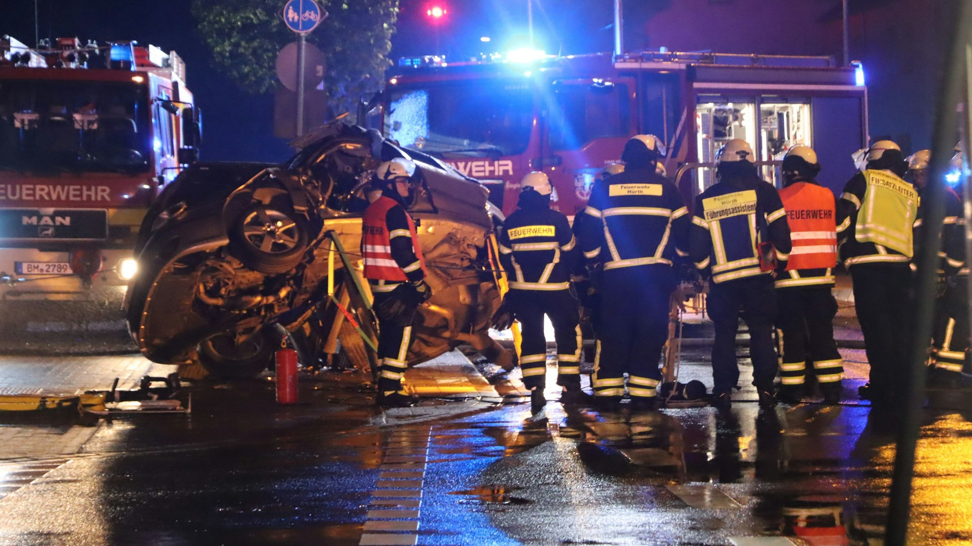Auf dem Foto ist das Wrack des Saab zu sehen. Feuerwehrmänner stehen am Unfallort.