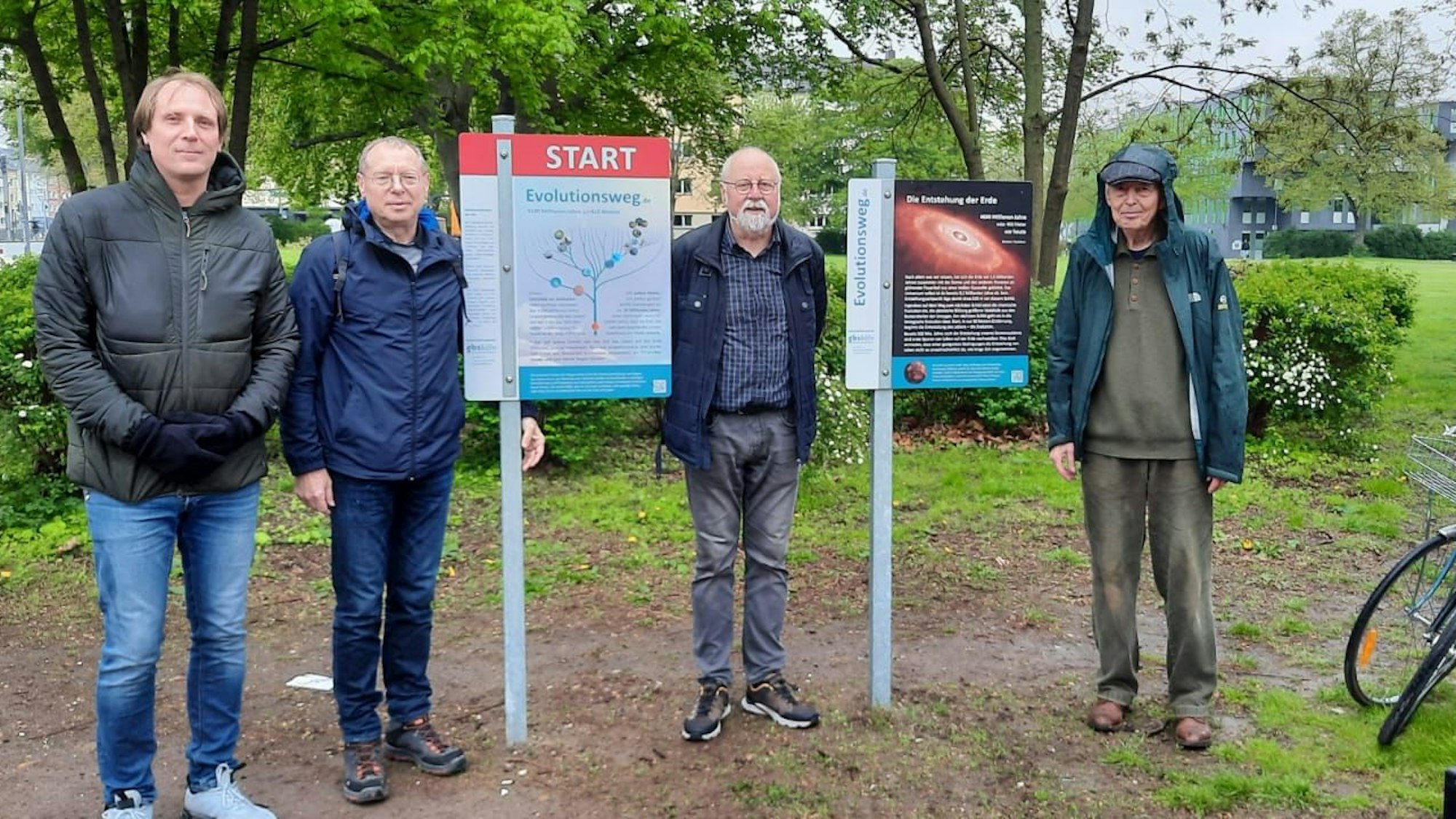 Vier Beteiligte stehen zwischen mehreren Info-Schildern.
