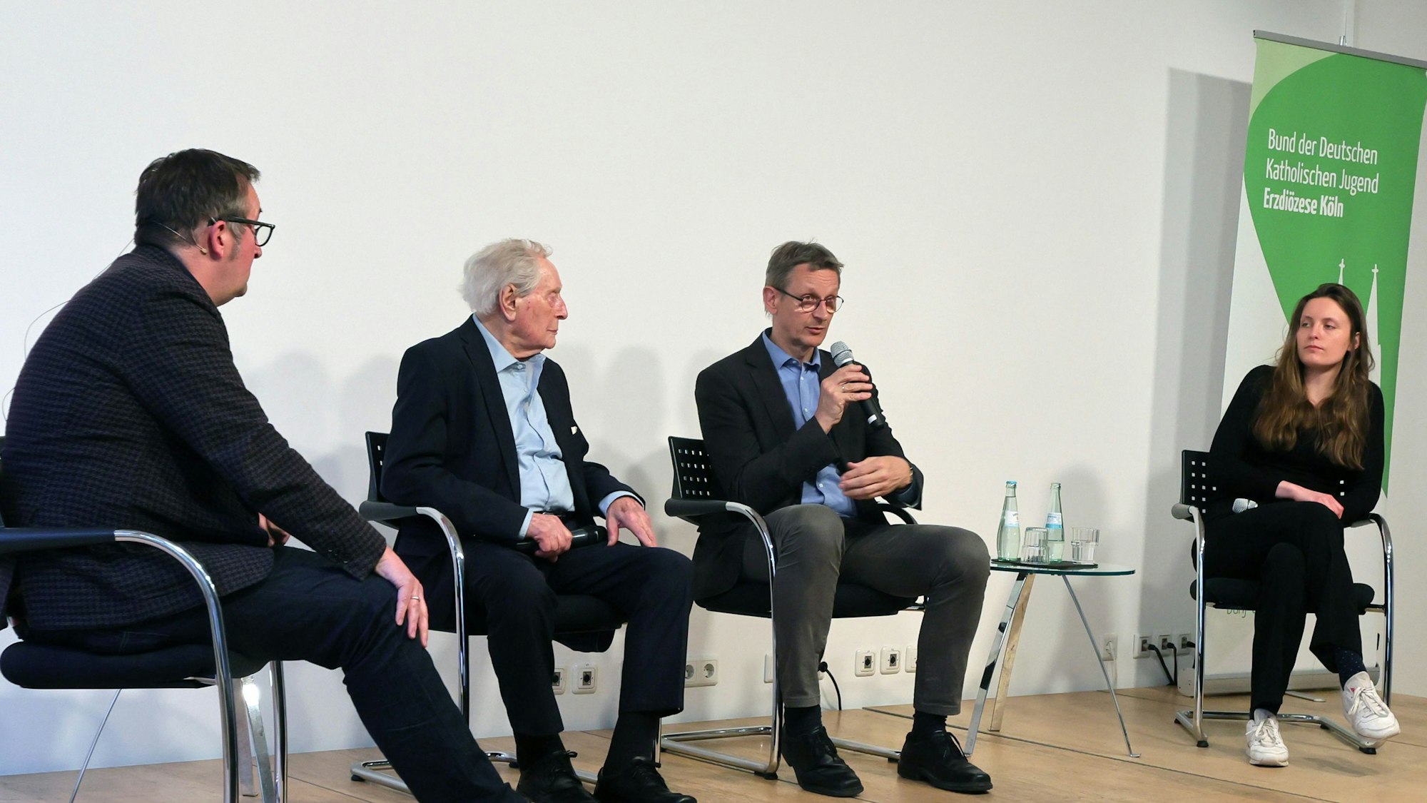 Die vier sitzen auf der Bühne der Akademie.