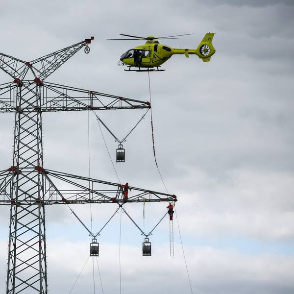 Schleswig-Holstein, Klixbüll: Ein Hubschrauber fliegt beim Einziehen der sogenannten Vorseile zwischen den Strommasten des letzten Bauabschnitts der Westküstenleitung. Mit dem Hubschrauber werden leichte Kunststoffseile von Mast zu Mast geflogen, Industriemonteure führen das Vorseil durch Rollen an den Mastenden. Die Westküstenleitung - eine 380-Kilovolt-Freileitung - wird über insgesamt rund 140 Kilometer zwischen Brunsbüttel und der dänischen Grenze und von dort weiter verlaufen.