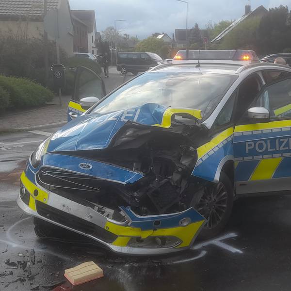 Ein Polizeiauto steht schwer beschädigt auf einer Kreuzung. Die linke Fron des Wagens ist aufgerissen und zerbeult.