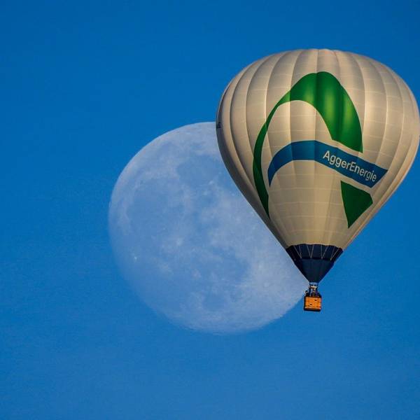 Ein Heißluftballon mit dem Logo der Aggerenergie fliegt am Himmel. Im Hintergrund des Ballons ist groß der Mond zu sehen.