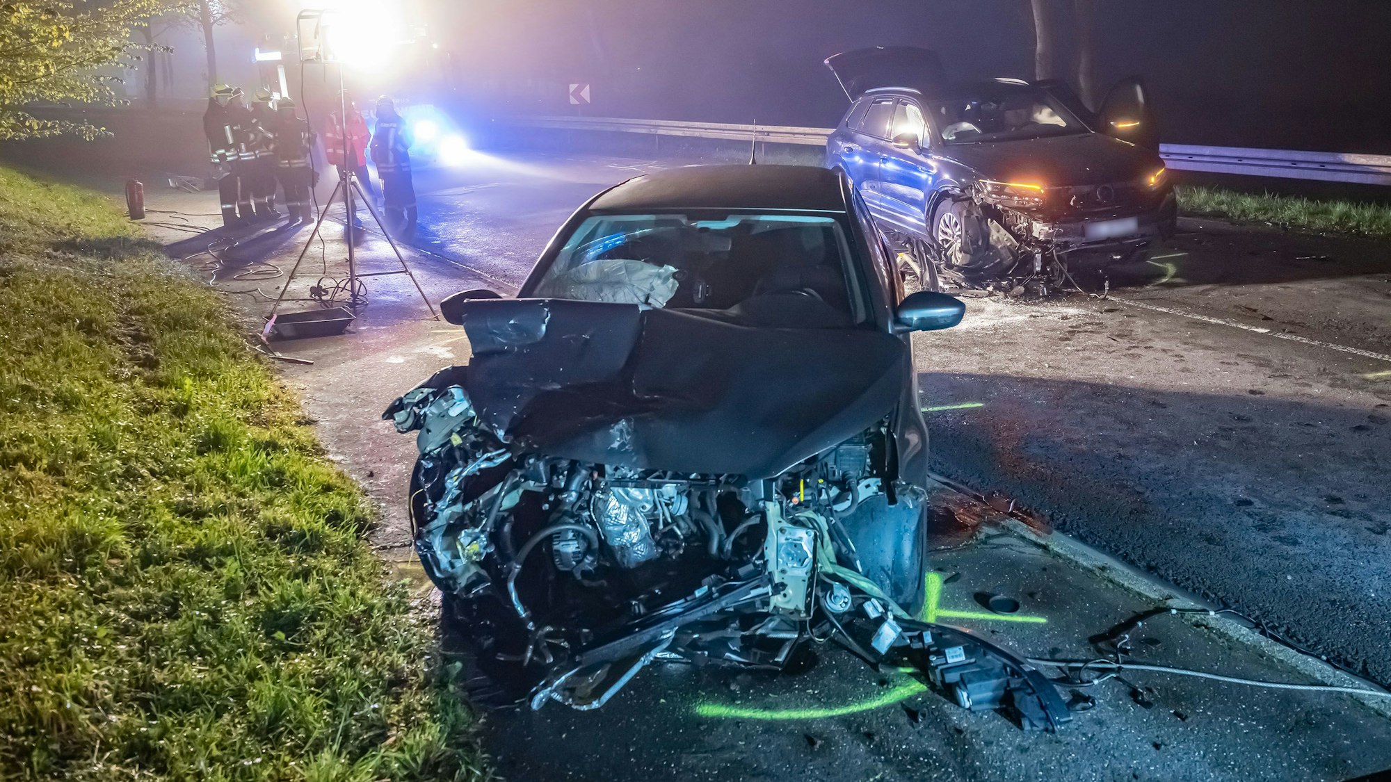 Unfallstelle in Wipperfürth-Hämmern. Zu sehen sind zwei beschädigte Pkw und Rettungskräfte im Hintergrund. Am Samstag (06. Mai) fuhr gegen 03:25 h ein VW-Geländewagen auf der B 237 in den Gegenverkehr und stieß dort mit einem entgegenkommenden Peugeot zusammen.