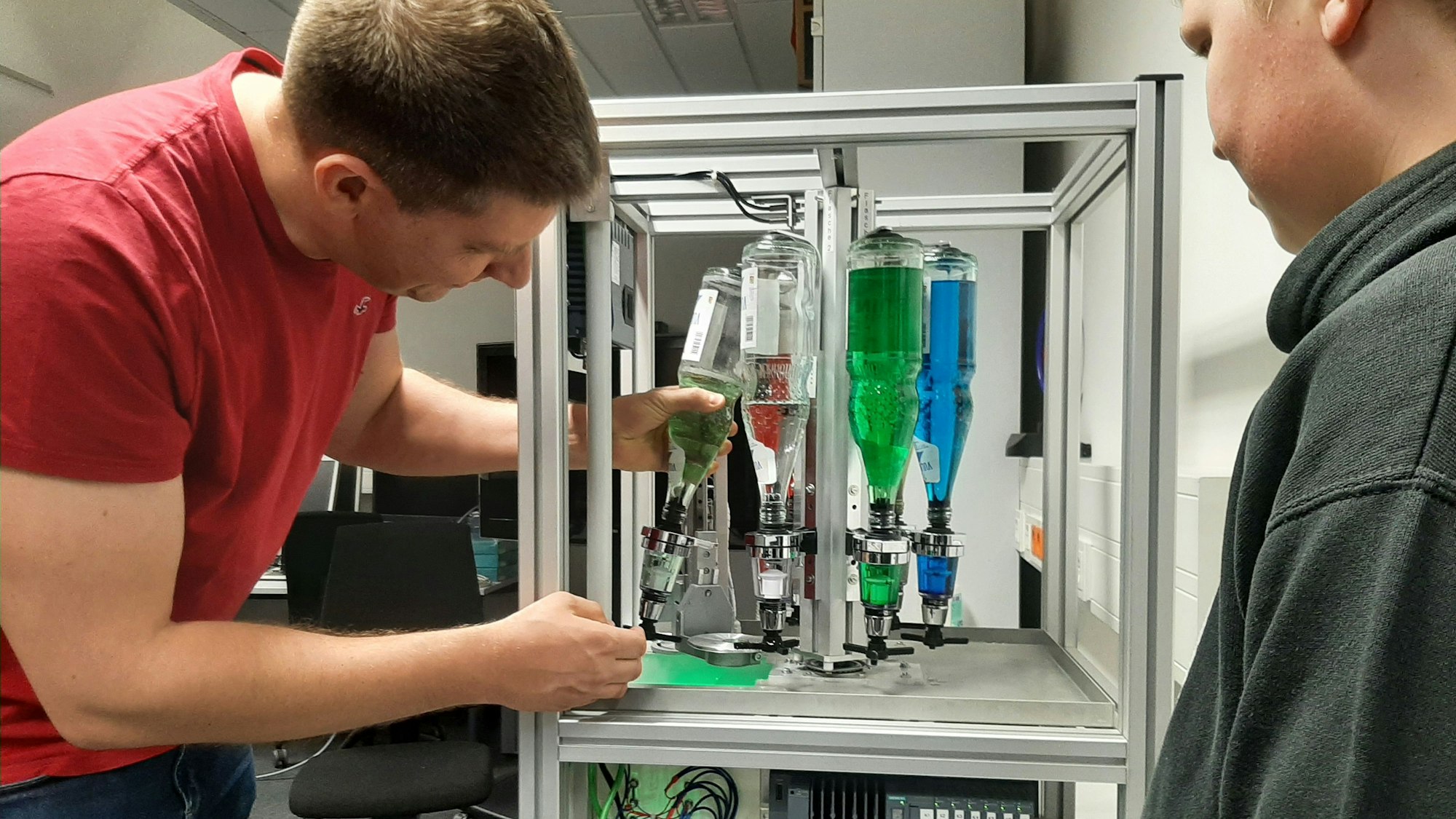 Ein Mann hantiert mit Flaschen, die in einer Apparatur eingespannt sind.