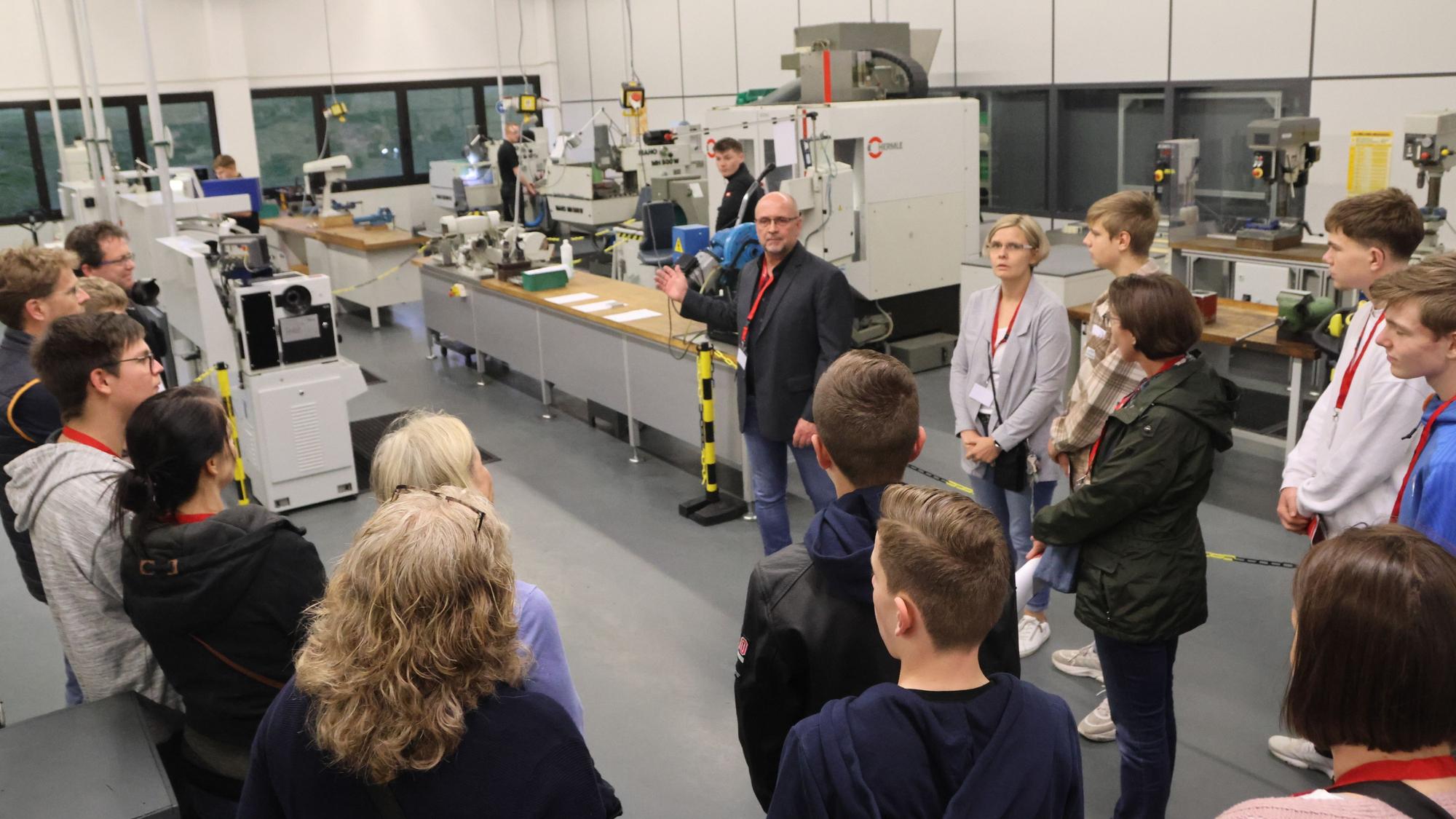 Ein Mann führt eine Besuchergruppe durch die Werkstatt eines Unternehmens.