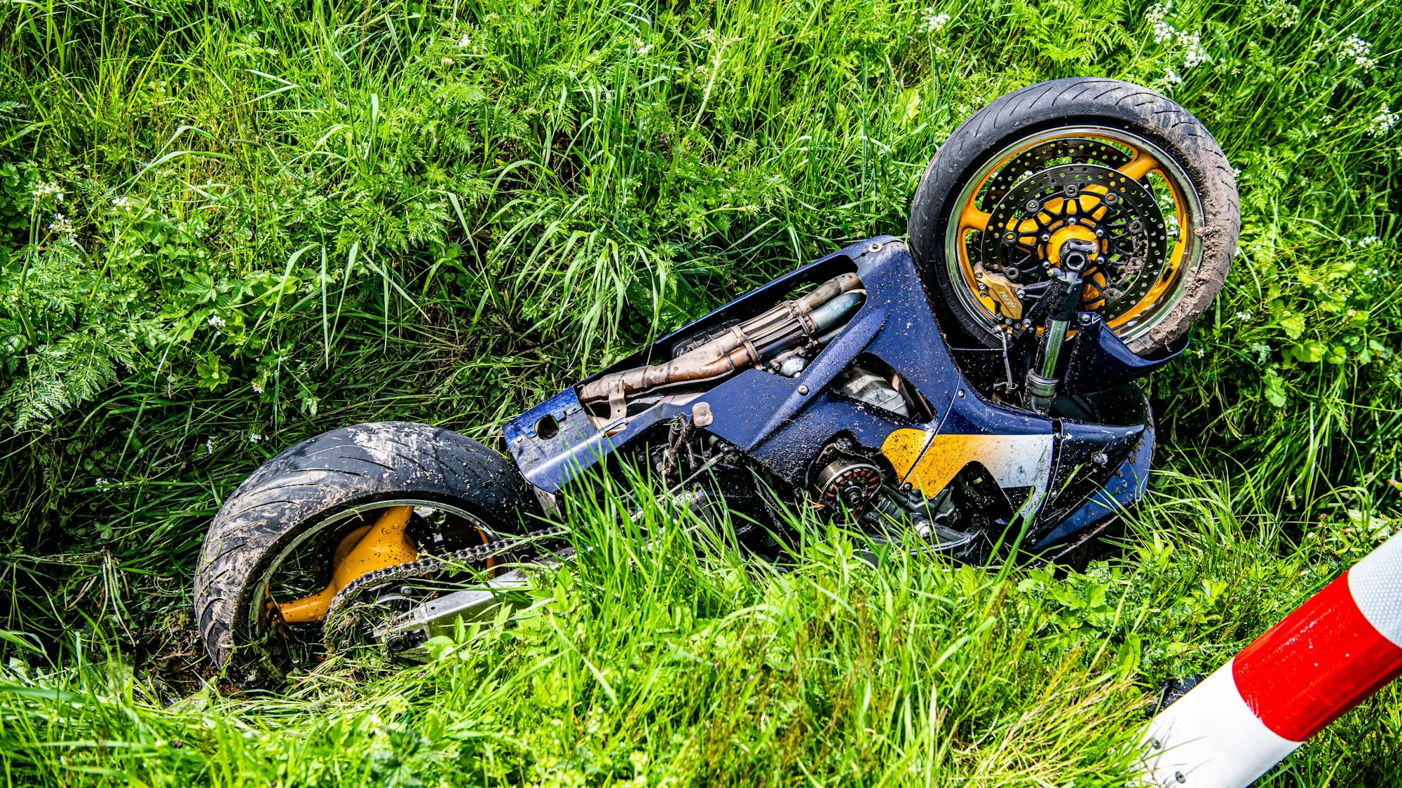 Ein Motorrad liegt nach Verkehrsunfall mit PKW-Beteiligung im Straßengraben.