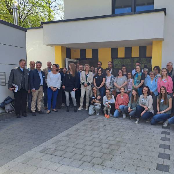 Vor dem Gebäude stehen Helfer und Helferinnen bei der Einweihung.