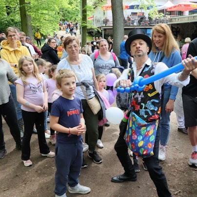 Ballonkünstler mit Kindern und Eltern.
