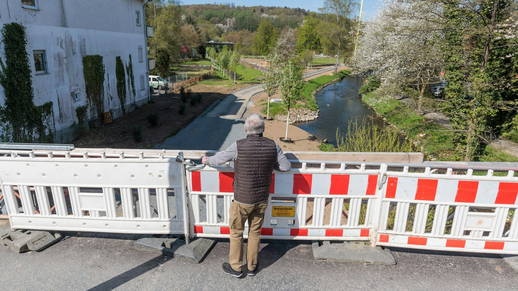 Zu sehen ist ein Mann vor einer Baustellenabsperrung, dahinter und unterhalb der neue Wiehlpark.