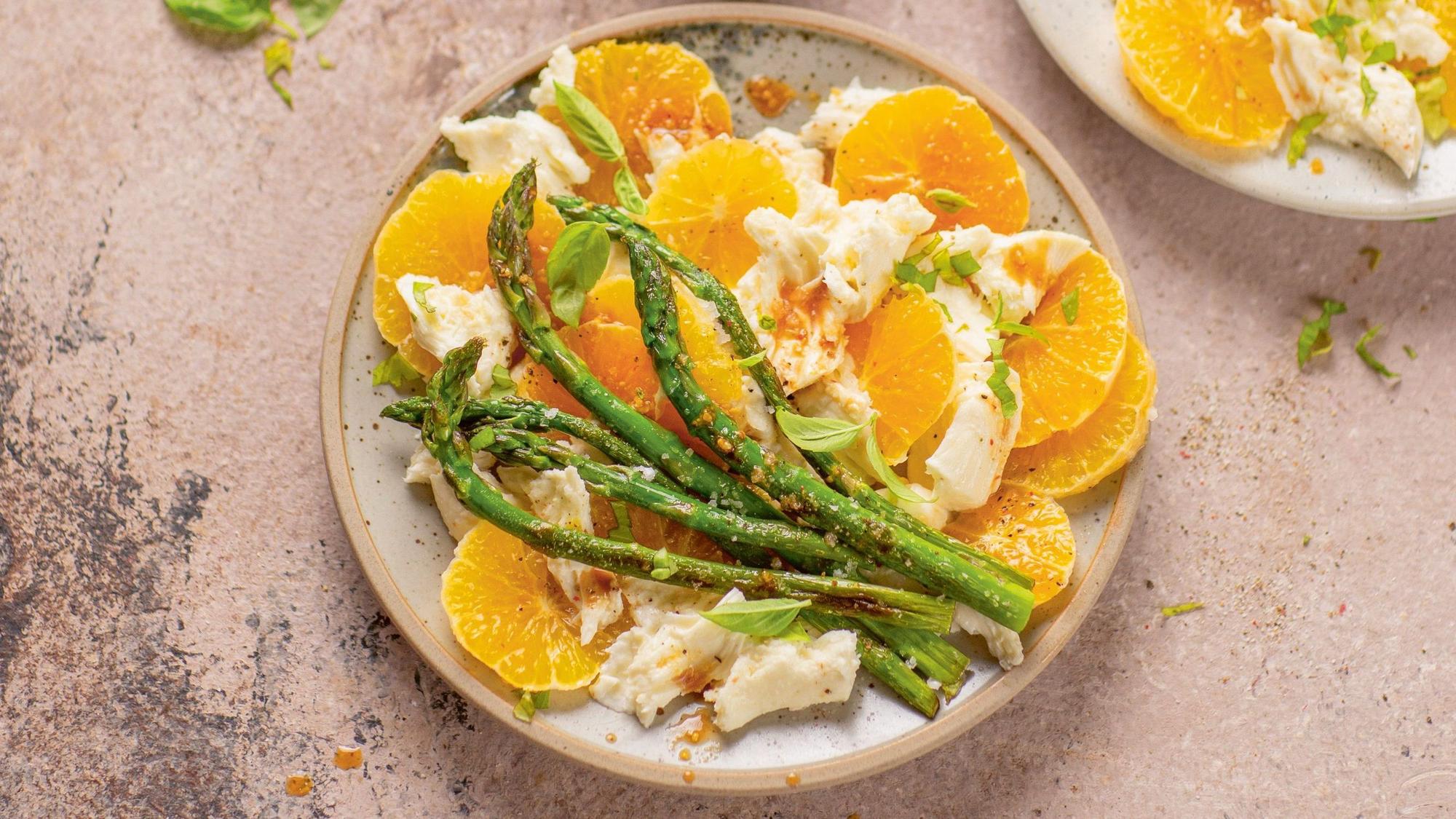 Orangenscheiben, Mozzarella und grüner Spargel angerichtet auf einem Teller