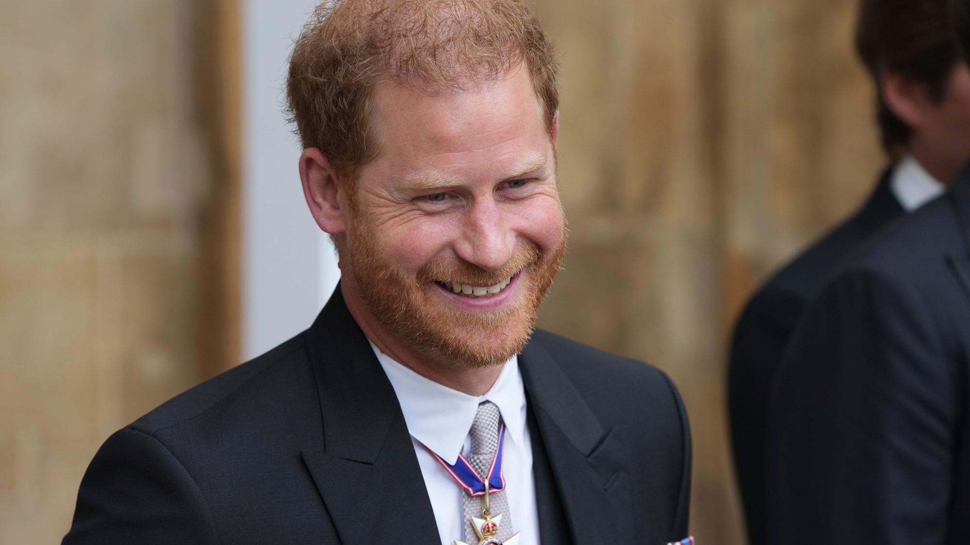 Prinz Harry, Herzog von Sussex, verlässt nach der Krönung von König Charles III. und Königin Camilla die Westminster Abbey und lächelt.