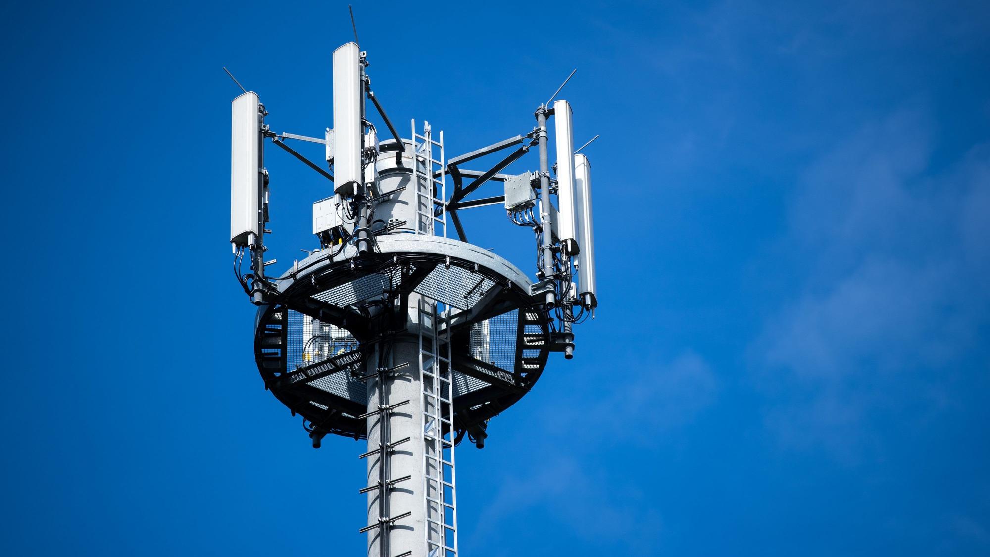 Ein Mast mit verschiedenen Antennen von Mobilfunkanbietern steht vor blauem Himmel.
Solche Antennen senden Funksignale an unsere Handys.