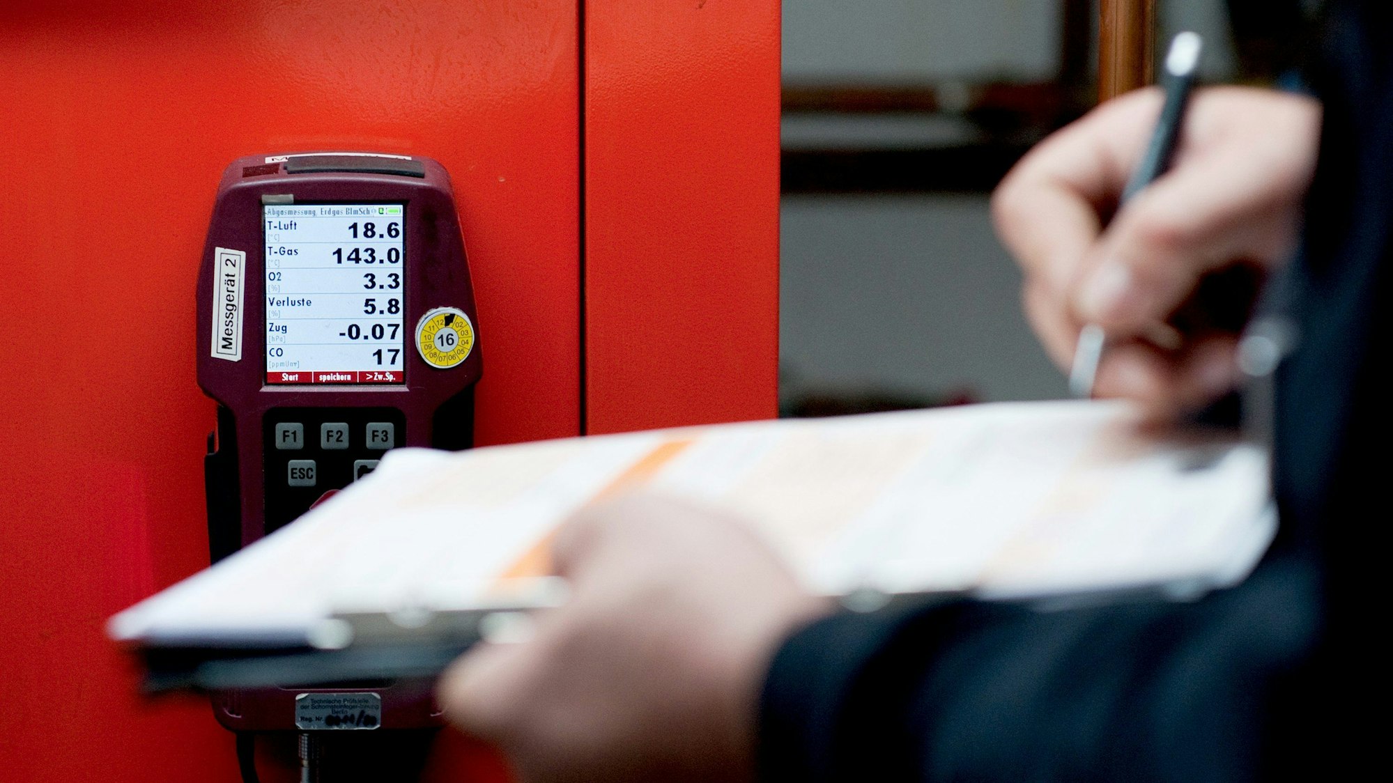 Ein Mensch füllt ein Formular vor einer Heizungsanlage aus