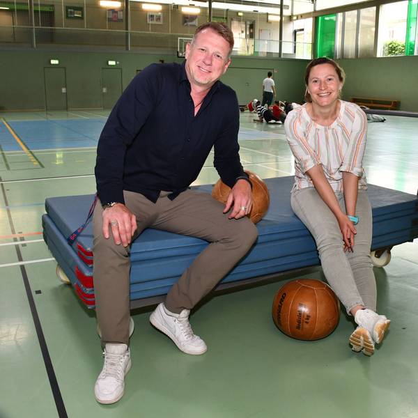 Sportlehrerin Diane Franzky und Schulleiter Carsten Balvin sitzen in der Sporthalle der Friedrich-Ebert-Realschule auf einem Mattenwagen.
