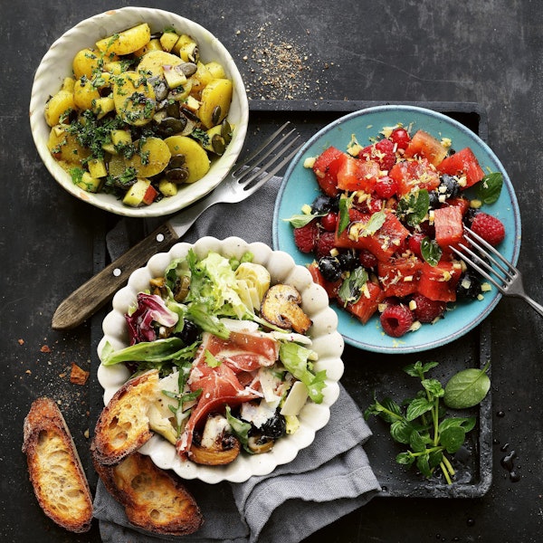 drei verschiedene Salate in Schalen und auf einem Teller