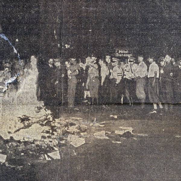 Auf dem schwarz-weiß-Foto ist ein brennender Scheiterhaufen zu sehen, zu seinen Füßen liegen ein paar unverberbrannte Bücher. Im Hintergrund einige Menschen, darunter auch einige in Uniform.