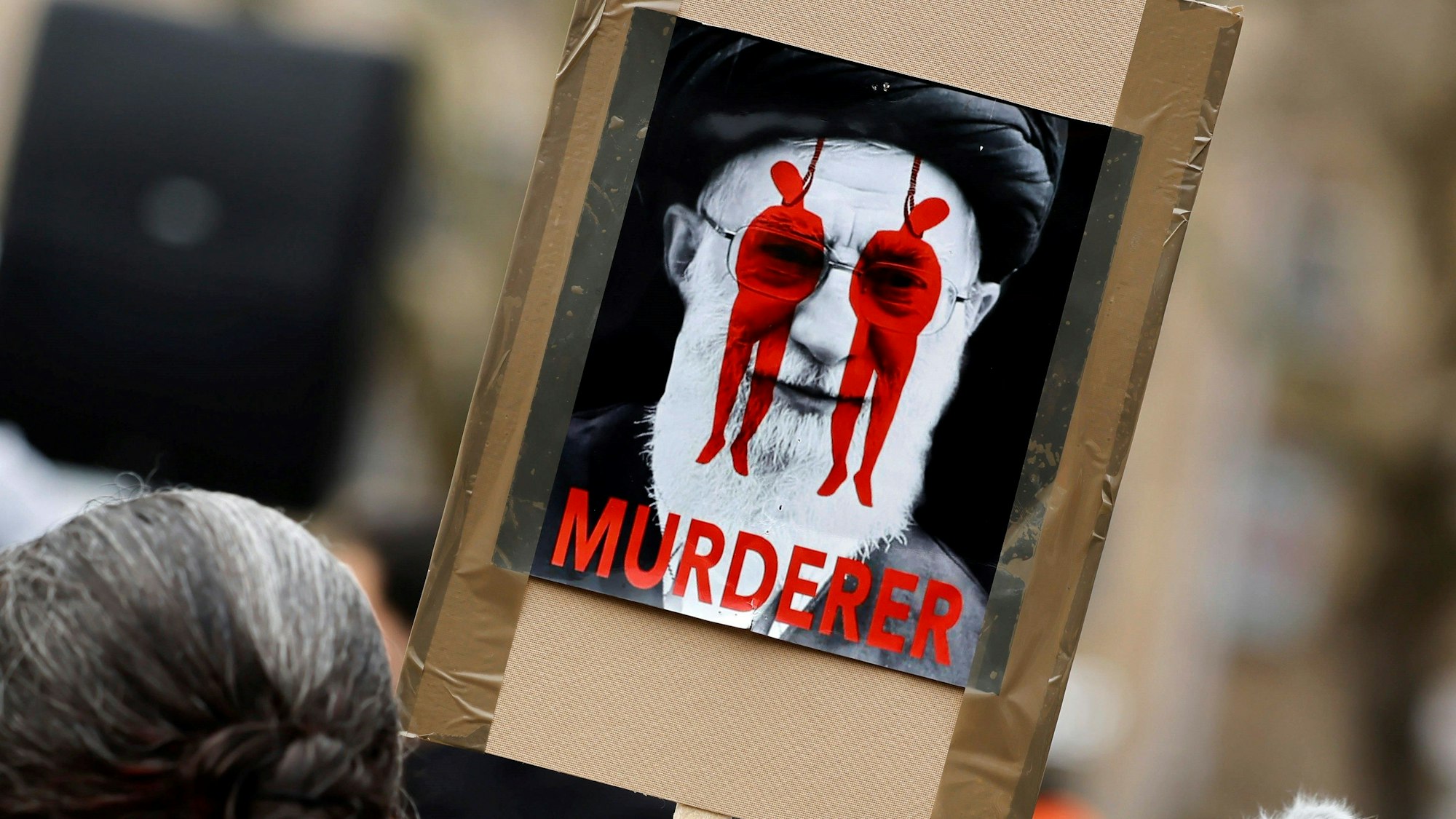 Die Hinrichtungen im Iran sorgen immer wieder für internationale Proteste. Ein Plakat bei einer Kundgebung in Köln zeigt das religiöse Oberhaupt des Iran, Ali Chamenei, mit dem Schriftzug „Mörder“. (Archivbild)