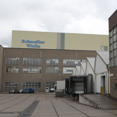 Mehrere Backsteingebäude eines Industriebaus, auf einem Gebäude steht der Schriftzug von Schoeller Wolle.